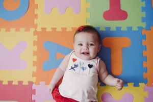 Baby girl sitting on a puzzle.