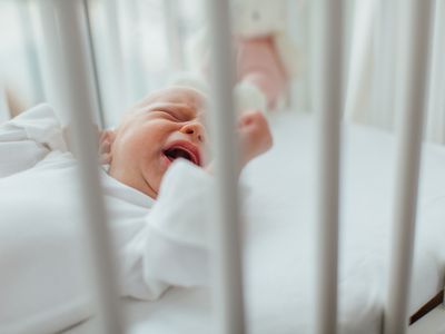 女婴躺在婴儿床上哭泣