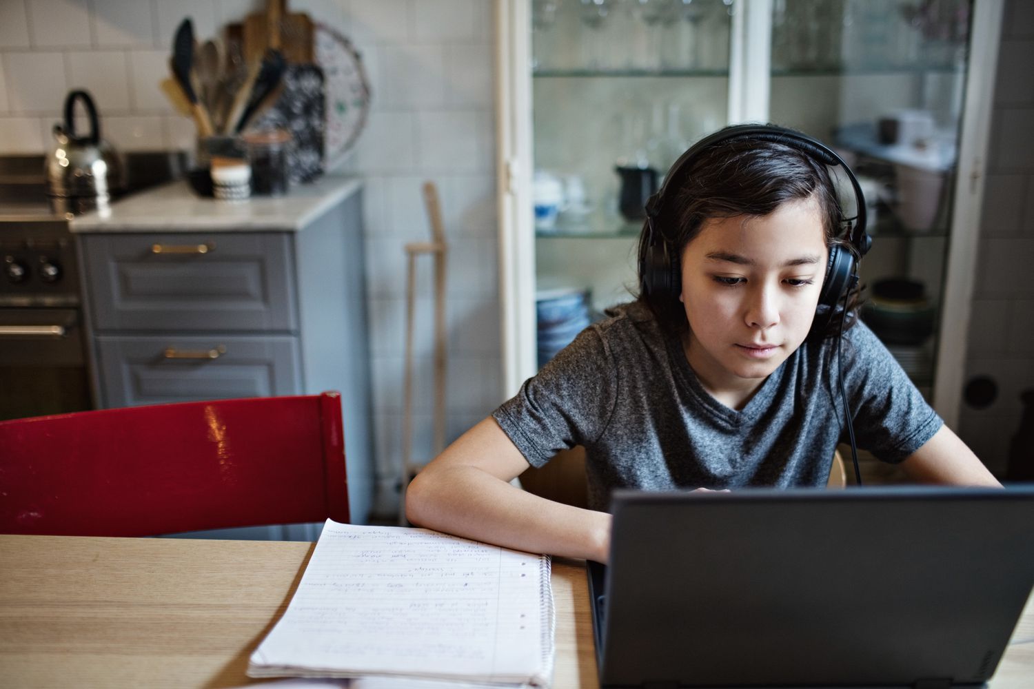 Boy wearing headphones while using laptop during homework at home