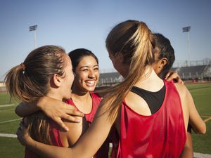 Teens on a soccer field hugging