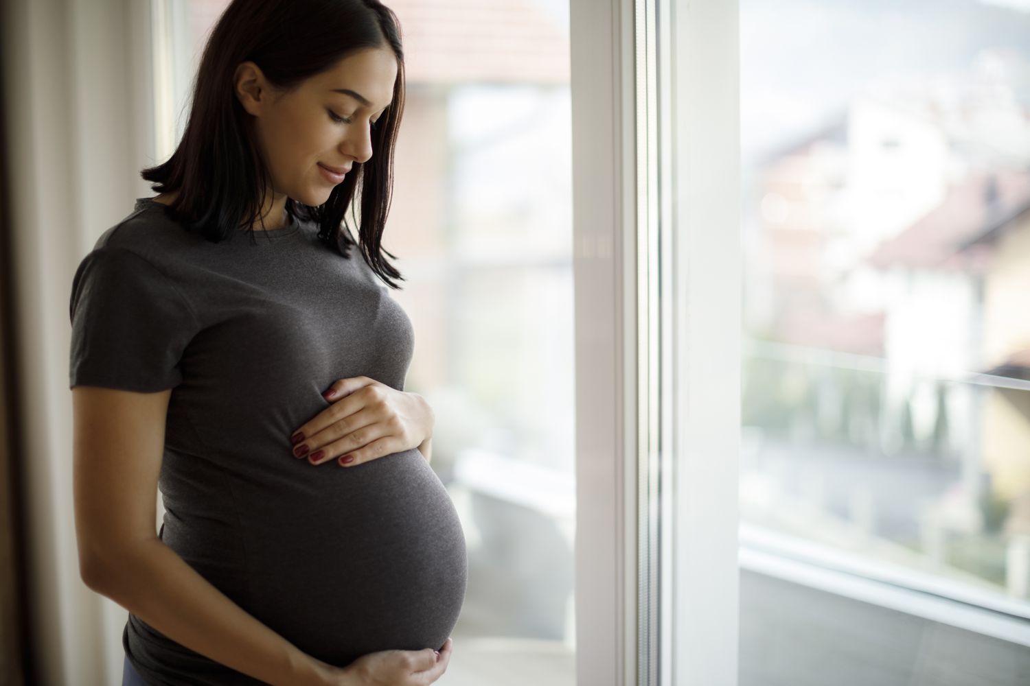 Pregnant woman standing by a window
