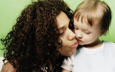 Woman embracing girl (2-4) indoors, close-up