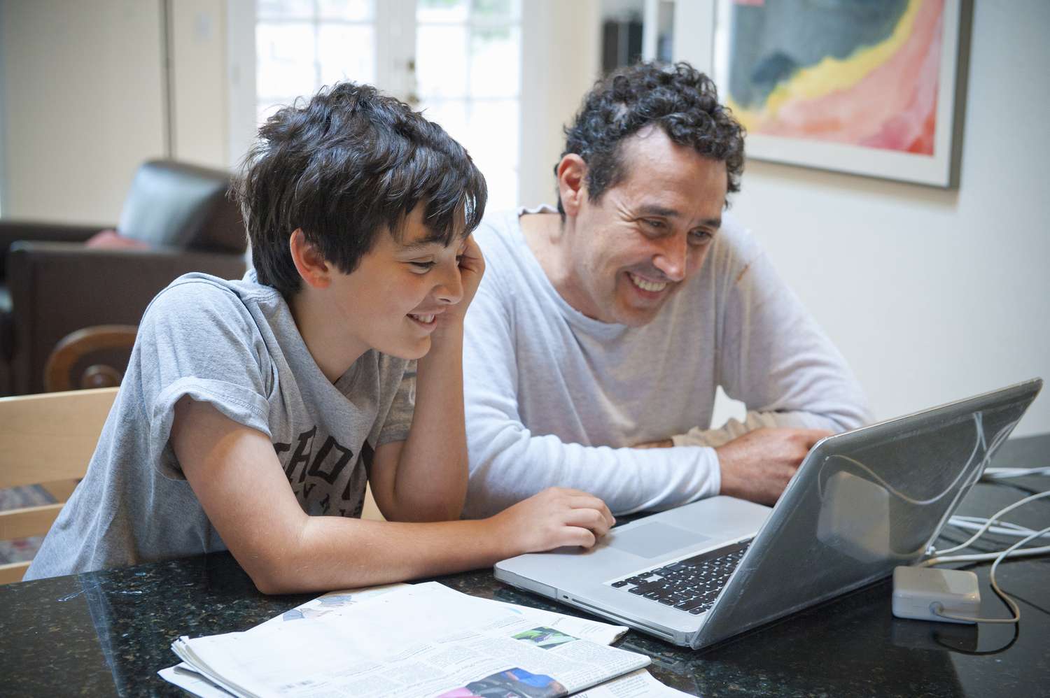 Father and son smiling while working at laptop