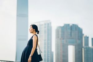 美丽的亚洲孕妇站在现代城市景观欣赏风景