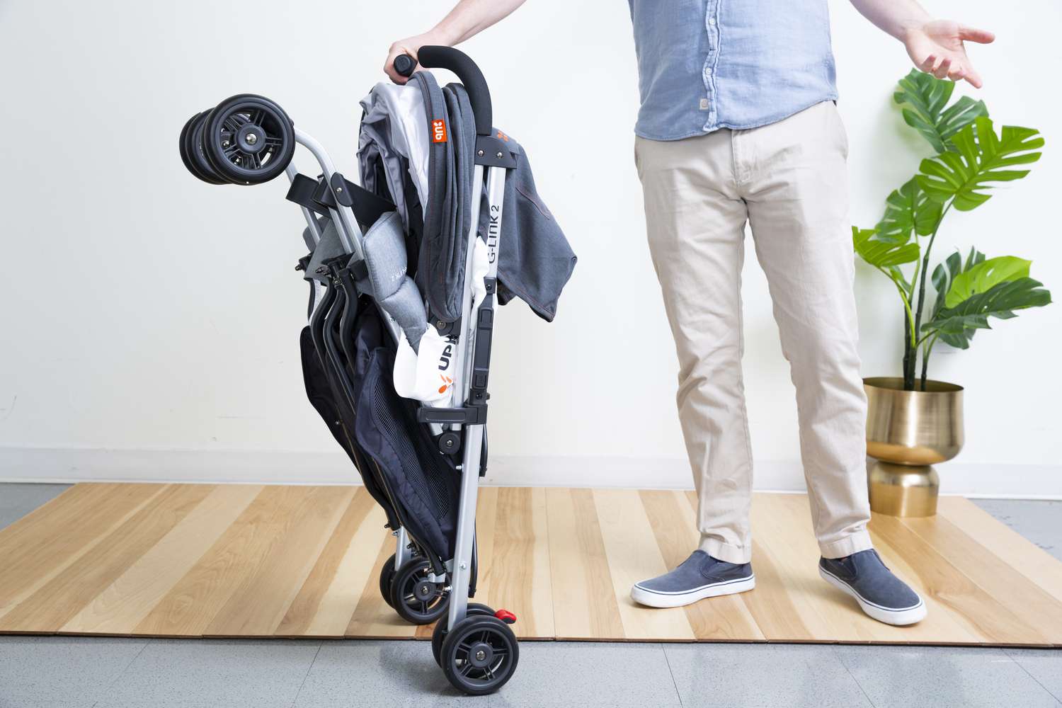 Person holding Uppababy G-Link 2 Double Stroller placed on carpet floor
