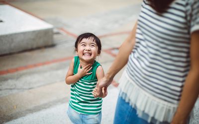 在公园里微笑着和妈妈手牵手的孩子