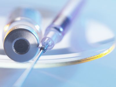 syringe and GnRH agonist vial with Lupron on glass dish, used during IVF treatment
