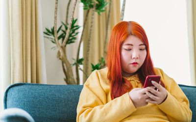 穿着黄色运动衫的亚洲少女看着她的手机