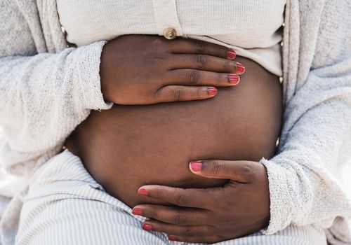 Black woman holding pregnant belly