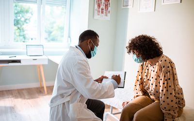 A doctor shows a patient notes in an examination room.