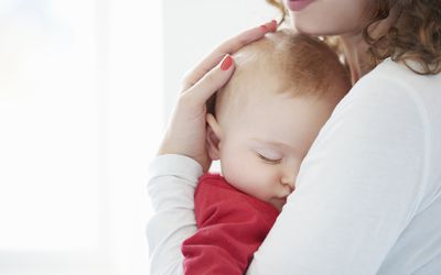 baby sleeping in the arms of mother