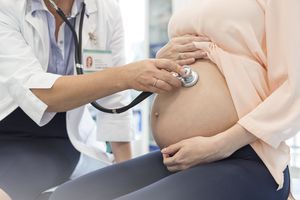 医生用听诊器检查孕妇胃部