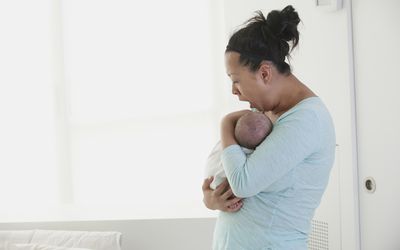 Yawning mother holding sleeping newborn