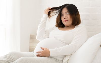一个孕妇把她的头发从头上扯下来。
