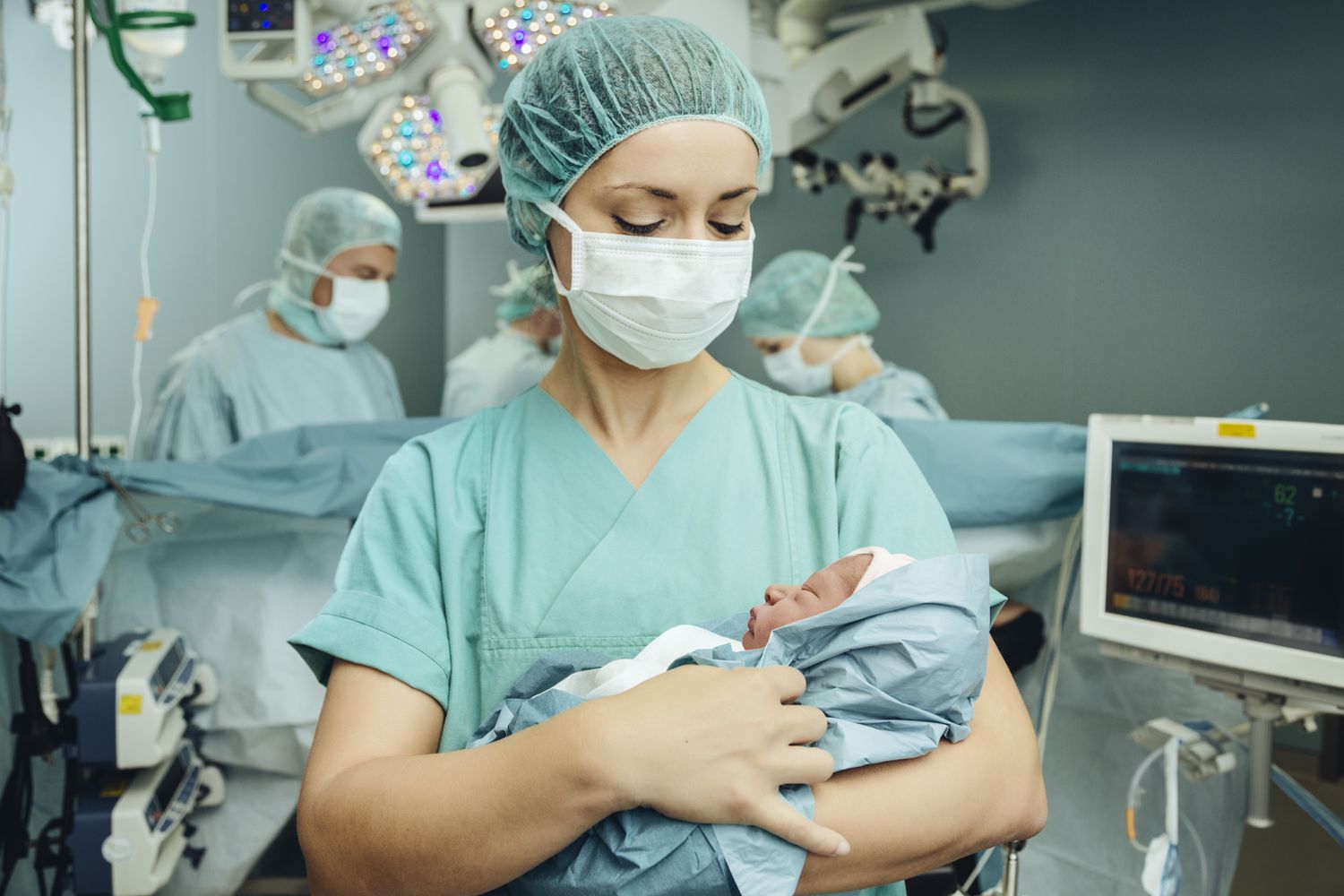 Operating room nurse holding newborn in operating room