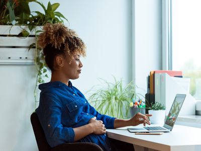 Pregnant woman with hand on belly using laptop