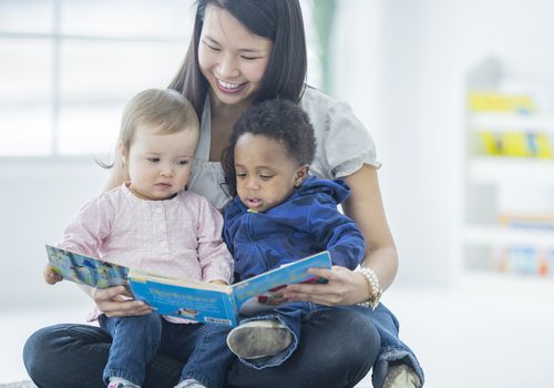 幼儿园老师给两个蹒跚学步的孩子读书