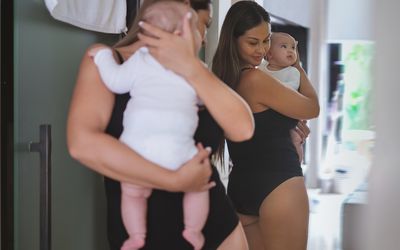 Woman holding baby looking at postpartum body