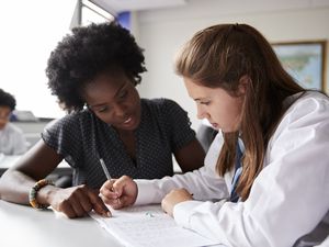 高中教师给穿制服的女学生一对一的课桌辅导