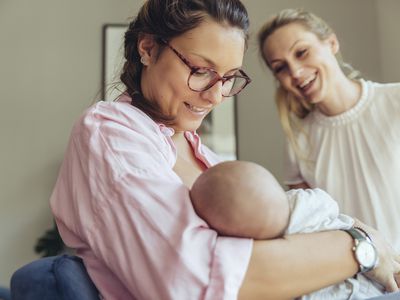 助产士扶着一位正在哺乳的母亲和她刚出生的婴儿