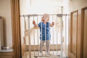 Small Boy Holds On To Safety Gate