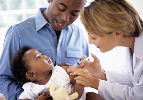 Doctor giving injection to baby boy (2-5 months)