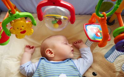 Baby boy sleeps peacefully on playmat