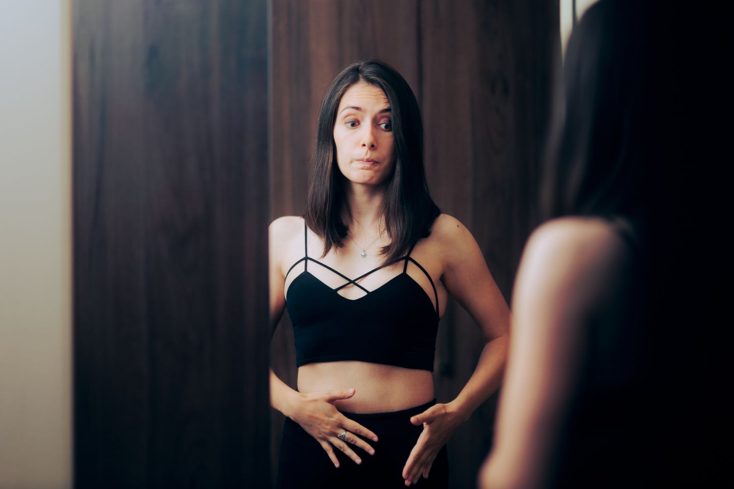 Woman Looking in Mirror Touching Belly