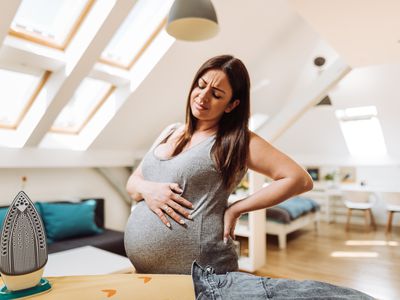 pregnant woman ironing and doing chores at home
