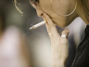 戴墨镜的年轻女子，在户外抽烟，特写