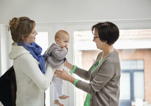 mom handing infant over to babysitter