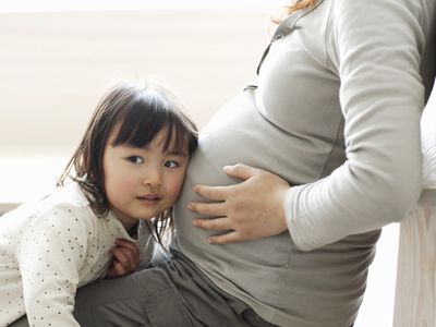 小女孩听着妈妈怀孕的肚子