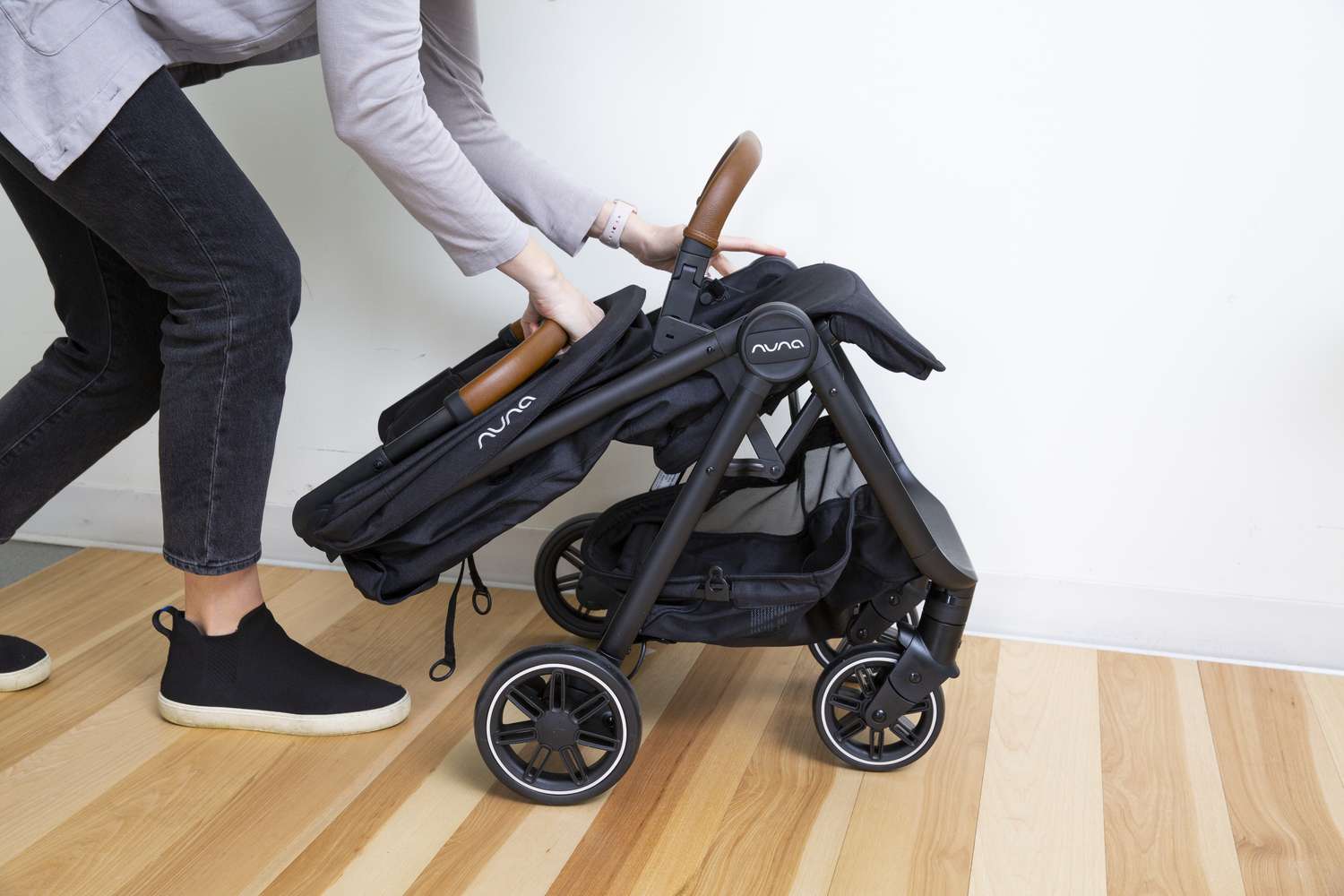 Person holding folded Nuna TRVL Stroller