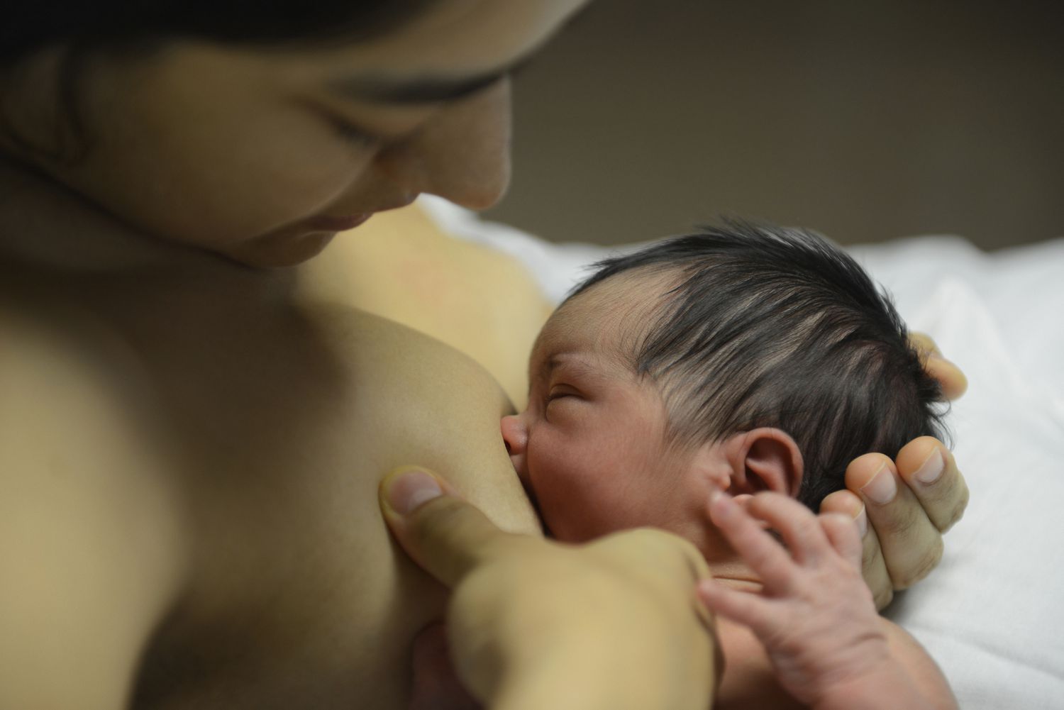 Hispanic mother breastfeeding newborn baby in a hospital