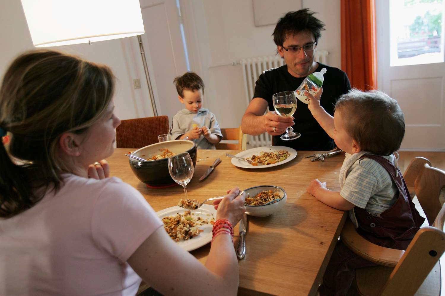 Mother and father sitting at the table with a baby and toddler