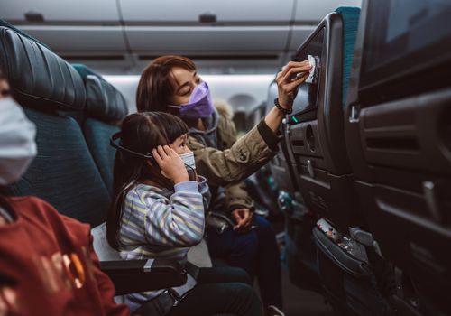 mom disinfecting tv screen for child on an airplane