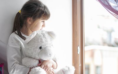 Little girl bored at home with her teddy bear