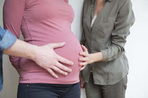 一个人的手和一个6个月的孕妇肚子上的女人的特写