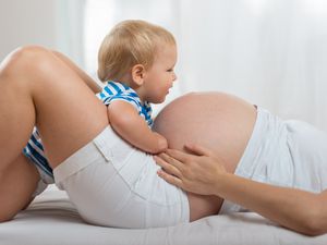 幸福的家庭。孩子男孩看着怀孕母亲的肚子