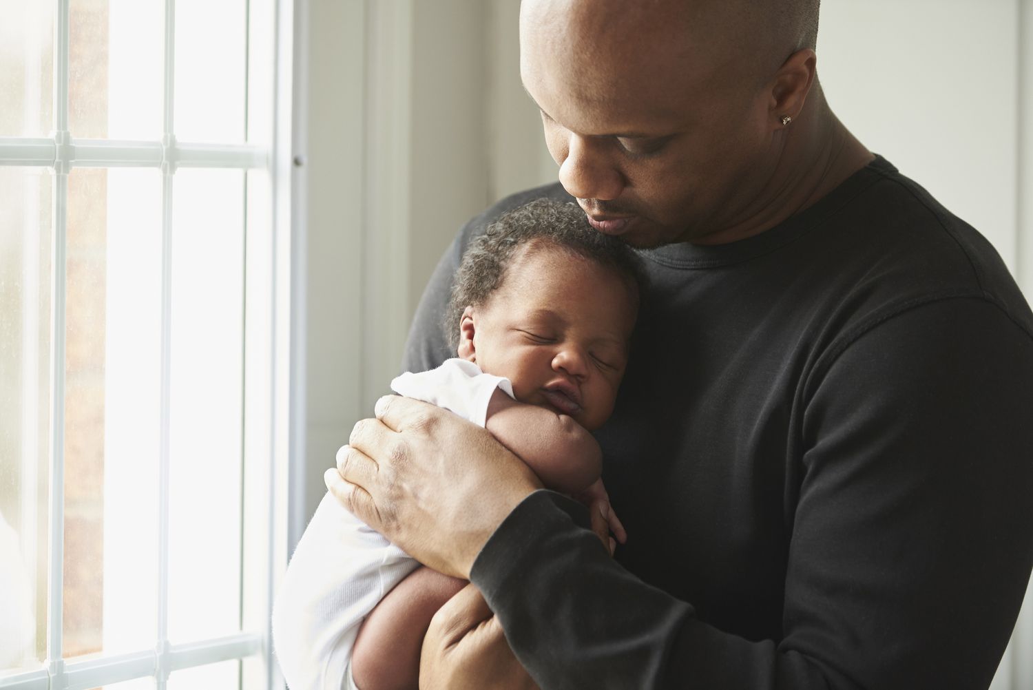Father holding baby boy beside a sunny window