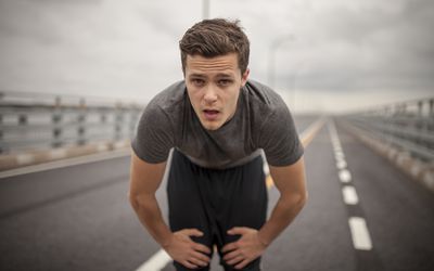 Man on long highway leaning over from fatigue, a possible symptoms of low testosterone levels