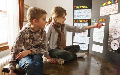 Girl explaining her science project to brother
