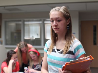 upset teen girl with other girls in the background