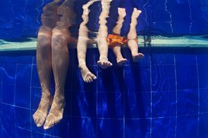 在水下的孩子的孩子在游泳上睡着脚上的妈妈
