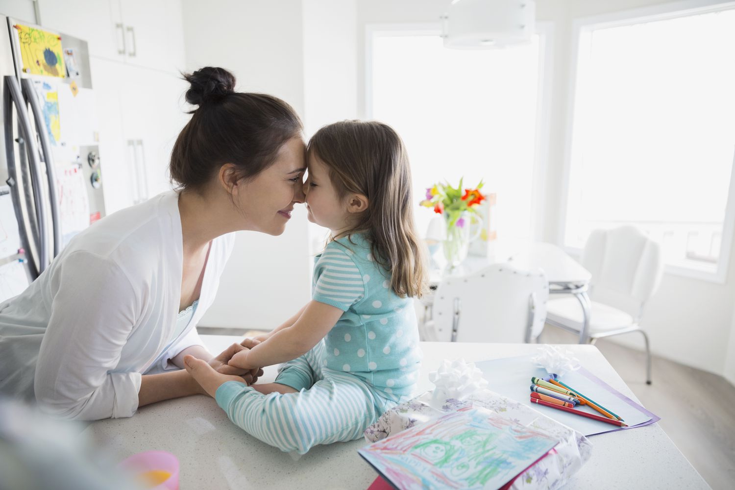 Affectionate mother and daughter rubbing noses in pajamas