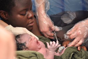 mom and baby with doctor cutting cord