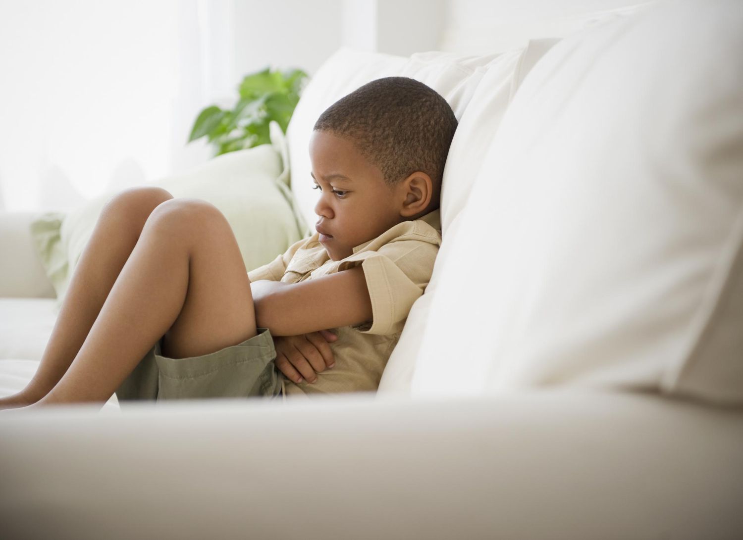 Little boy sitting with folded arms on the couch in time-out