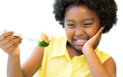 young girl making face eating vegetables