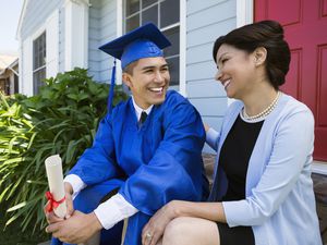 Smiling graduate and mother on front stoop