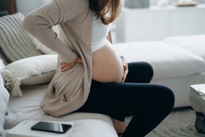 Woman sitting on a couch holding her pregnant belly